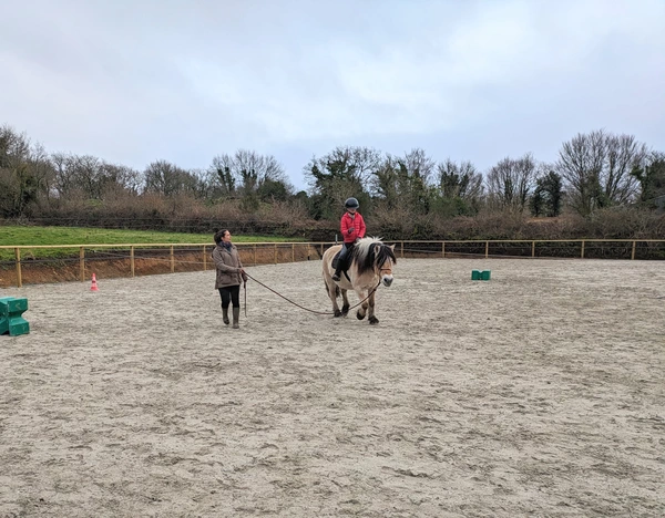 La monitrice longe un poney monté par un enfant