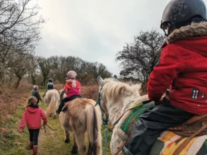 un groupe d'enfant sur des poneys tenus en main